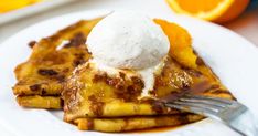 a white plate topped with waffles covered in syrup and ice cream next to orange slices