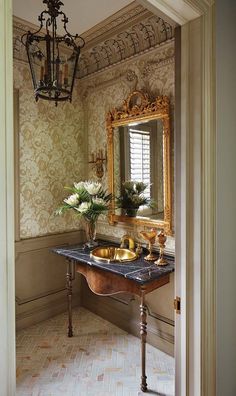 an ornate bathroom with gold fixtures and marble counter tops, along with a chandelier