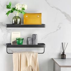 two black shelves with towels, vases and other items on them in a bathroom