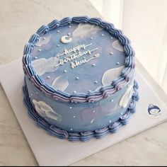 a blue birthday cake sitting on top of a white countertop next to a window