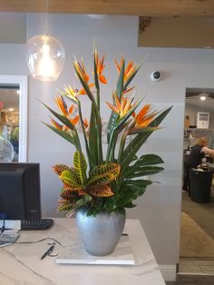 a vase filled with flowers sitting on top of a counter next to a computer monitor