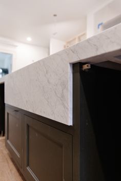 a kitchen counter with marble top and black cabinetry in the backround area