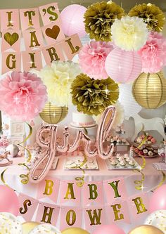 it's a girl baby shower party with pink, gold and white decorations including tissue pom poms