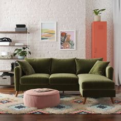 a living room with a green couch and ottoman in front of a white brick wall