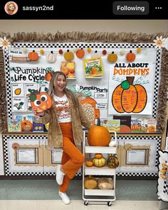 a woman standing next to a display of pumpkins in front of a bulletin board