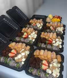 several trays filled with different types of food on top of a white tablecloth