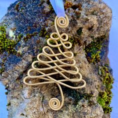 a wire wrapped christmas tree ornament on a rock