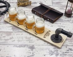 there are five mugs with beer in them sitting on a wooden table next to an old book