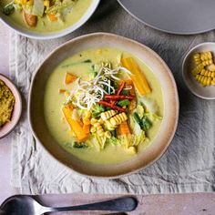 two bowls filled with soup next to corn on the cob and other food items