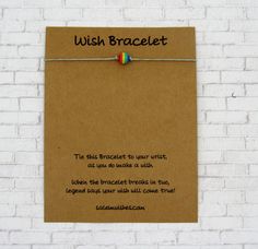 a note attached to a brick wall that says wish brocelet with a rainbow bead on it