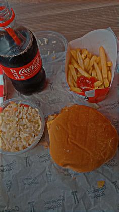 a table topped with lots of food next to a bottle of coca cola and french fries