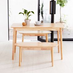 two wooden tables sitting next to each other on top of a white tile floor near potted plants