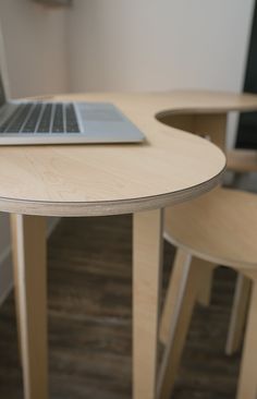 an open laptop computer sitting on top of a wooden table next to two stools