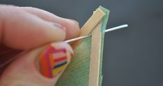 a person is holding a pair of scissors and knitting needles in front of a piece of fabric