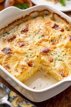 a casserole dish with cheese and parsley on the side, ready to be eaten