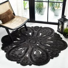 a chair sitting in front of a window next to a black rug on the floor