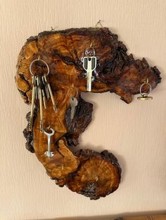 there is a piece of wood with keys attached to it and some key hooks hanging on the wall