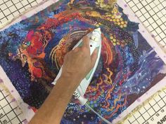 a person is using a video game controller on a piece of fabric with an intricate design