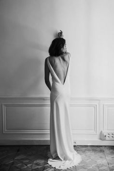 the back of a woman's dress standing in front of a wall