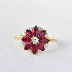 a close up of a ring on a white surface with red and white stones in the middle