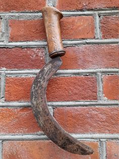 an old metal hook on the side of a brick wall with a wooden tube sticking out of it