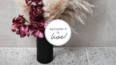 a black vase filled with purple flowers on top of a marble floor next to a sign that says episode 4 is live