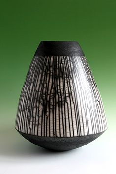 a black and white vase sitting on top of a green table next to a wall