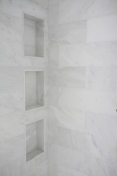 a white tiled shower with shelves on the wall