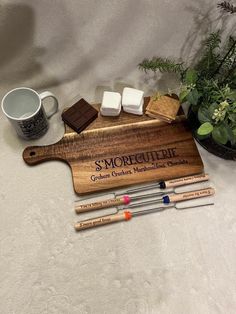 some chocolates and marshmallows on a wooden cutting board next to a cup