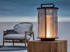 a lamp sitting on top of a wooden block next to a chair and couch in the background