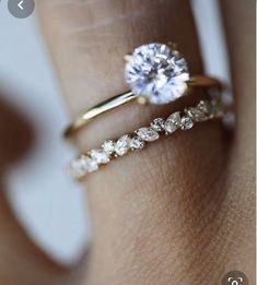 a woman's hand with two gold rings and a diamond ring on her finger