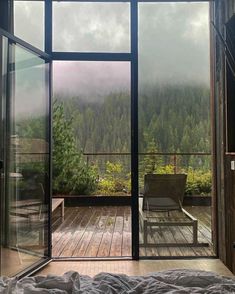 a bed sitting on top of a wooden floor next to an open glass door with trees in the background