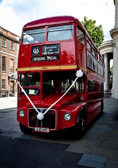 a red double decker bus parked on the side of the road in front of a building