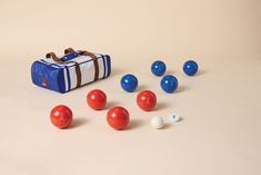 an assortment of balls and bowling equipment on a white surface with a blue bag in the background