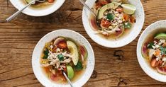 four bowls filled with food on top of a wooden table