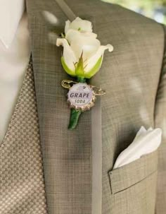 a boutonniere with a white rose attached to the lapel of a suit