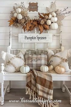 a white bench topped with lots of pillows and pumpkins next to a sign that says pumpkin season