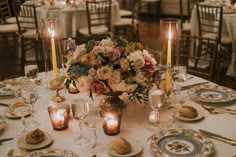 the table is set with candles, plates and silverware for an elegant wedding reception