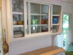 a kitchen cabinet with glass doors and plates