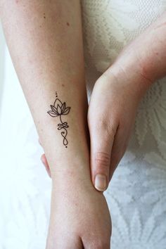 a woman with a tattoo on her arm holding the hand of another person's wrist