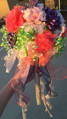 a bridal bouquet with ribbons and flowers on the handlebars is being held by someone's hand