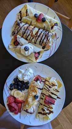 two white plates topped with desserts and fruit on top of a wooden table next to each other