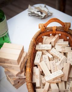 a basket full of wooden blocks sitting on top of a table next to a bottle