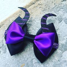 a purple and black bow tie laying on top of a cement slab next to a wall