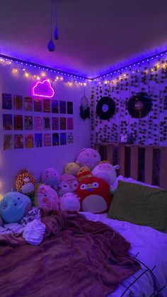 a bed with lots of stuffed animals on it in a room that has purple lights