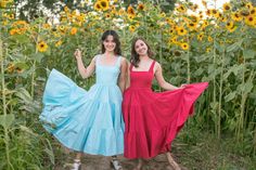 two women in dresses are standing next to each other with sunflowers behind them