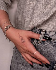 a woman's hand with a small flower tattoo on her left wrist and bracelet