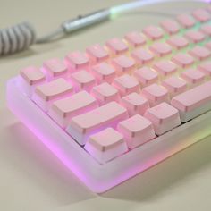 a pink keyboard sitting on top of a table next to a white cordless mouse