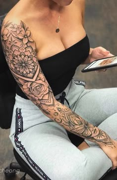 a woman with a tattoo on her arm is sitting down and holding a cell phone