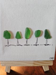 four green trees are shown in the middle of an art work on a piece of paper